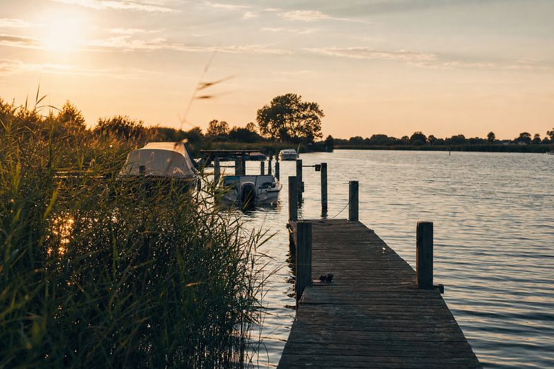 Houten steiger met aanlegpalen in een rustige rivierarm bij zonsondergang